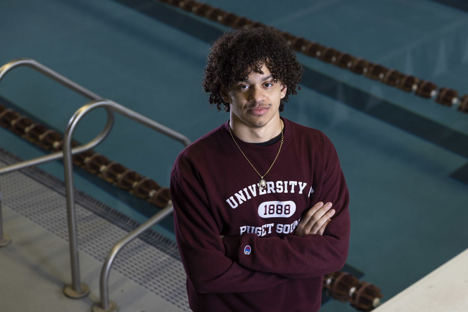 Jaden Francis ’25 stands in the Athletics and Aquatics Center, with the pool immediately behind him