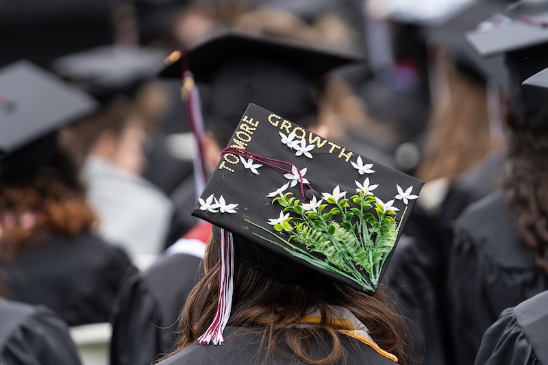 A graduation cap is seen with flowers decorating the top and the words "More to Grow" on the top. 
