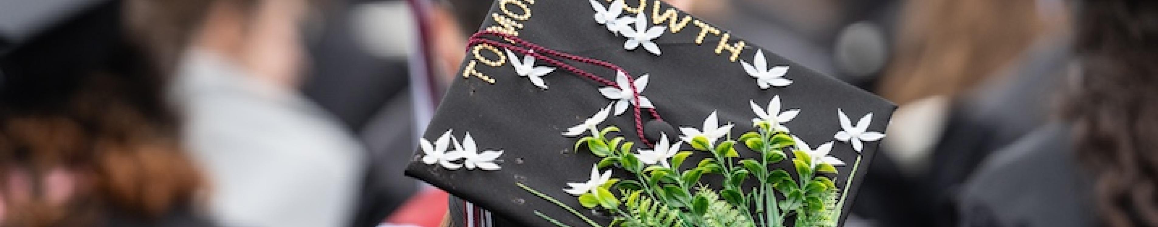 A graduation cap is seen with flowers decorating the top and the words "More to Grow" on the top. 