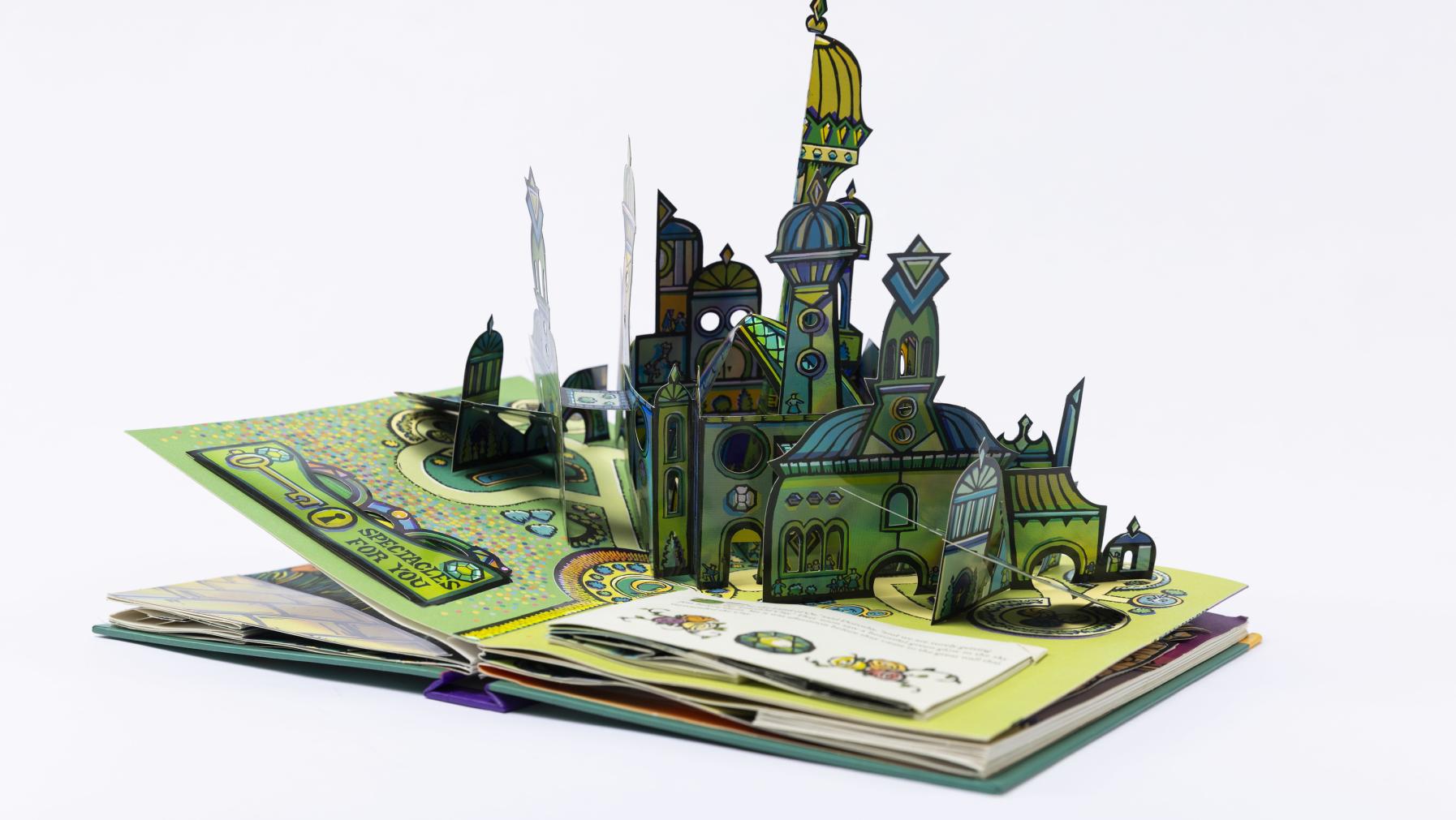 The Emerald City emerges from the pages of a pop-up book version of The Wizard of Oz.