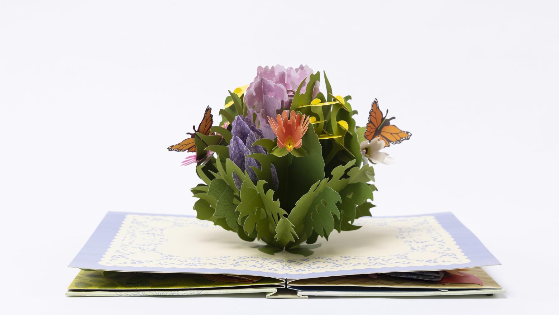 An open page of a pop-up book featuring bouquets of paper flowers.