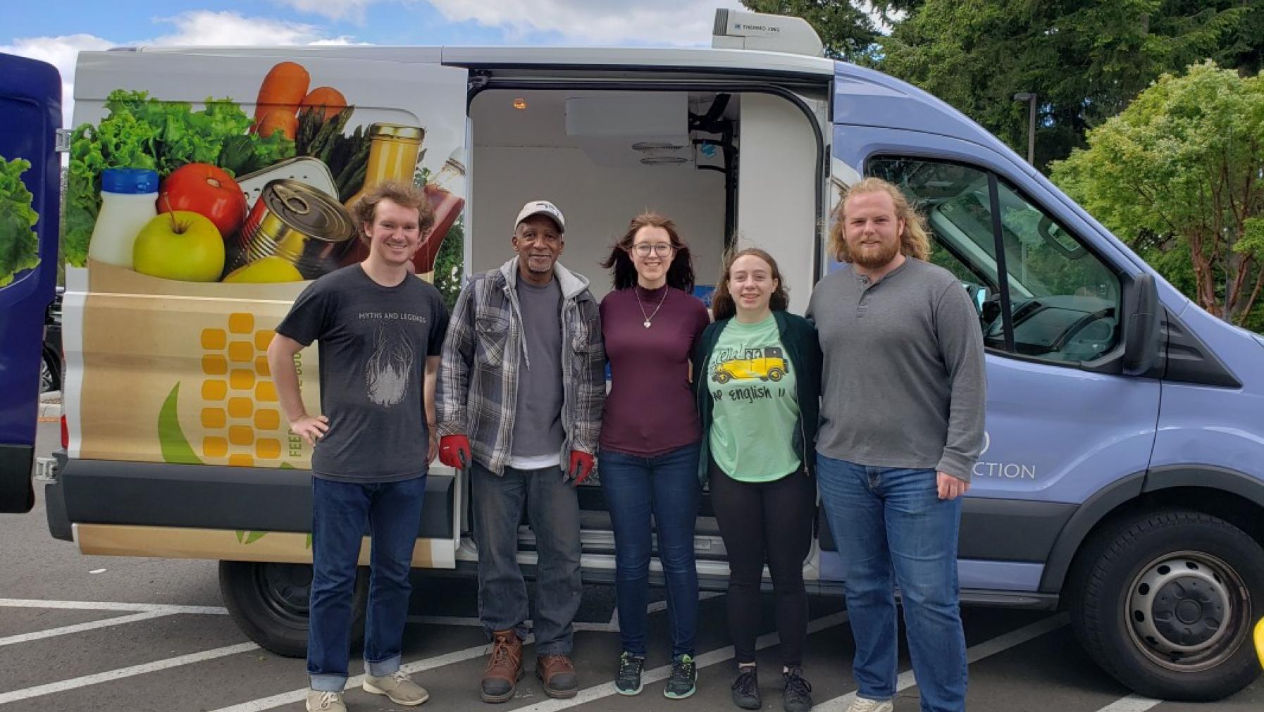 Five people standing in front of a van.