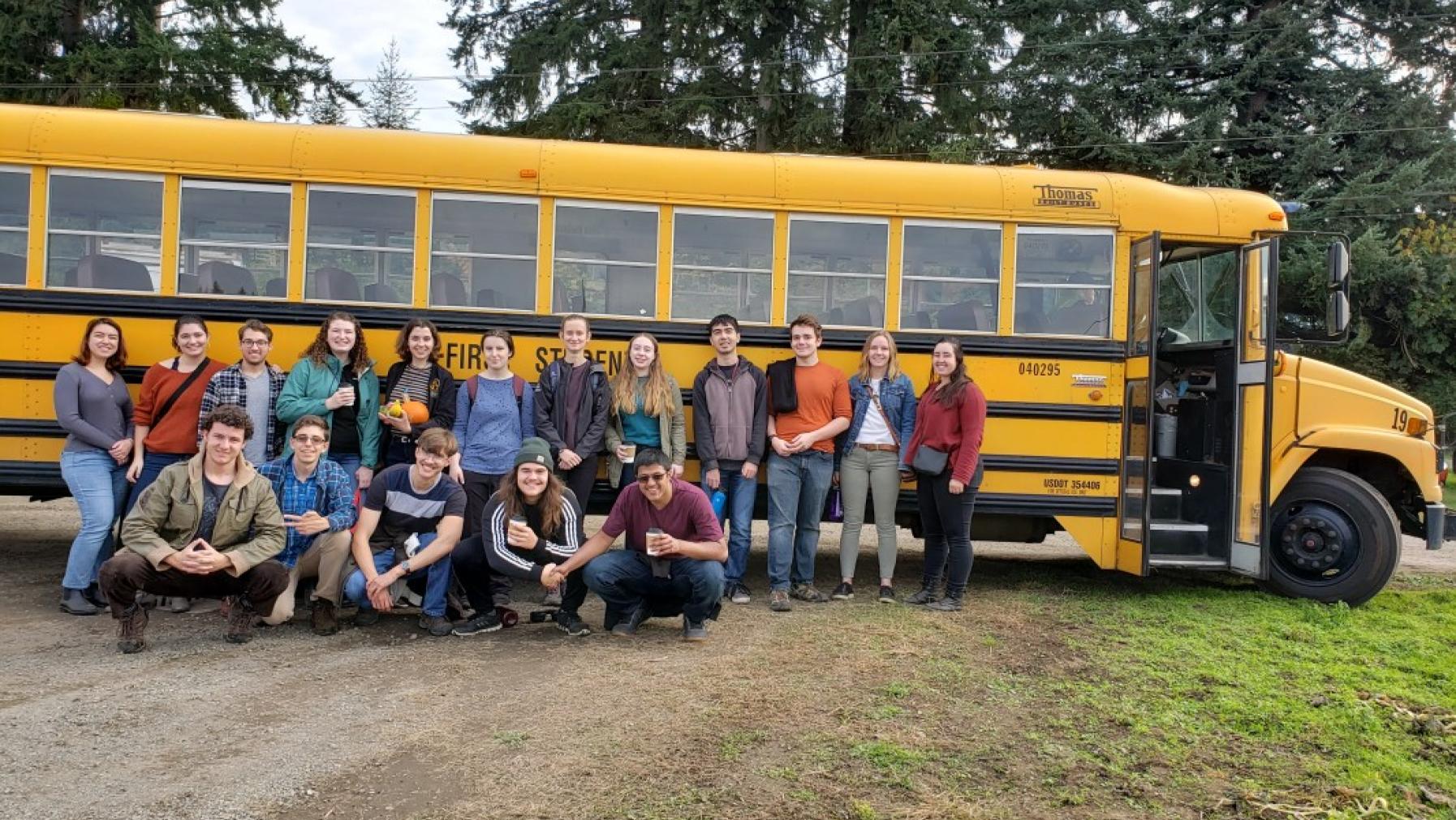 A group of people in front of a bus.