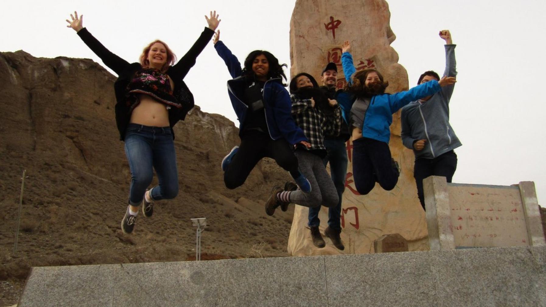 Some people jumping in front of a monument.