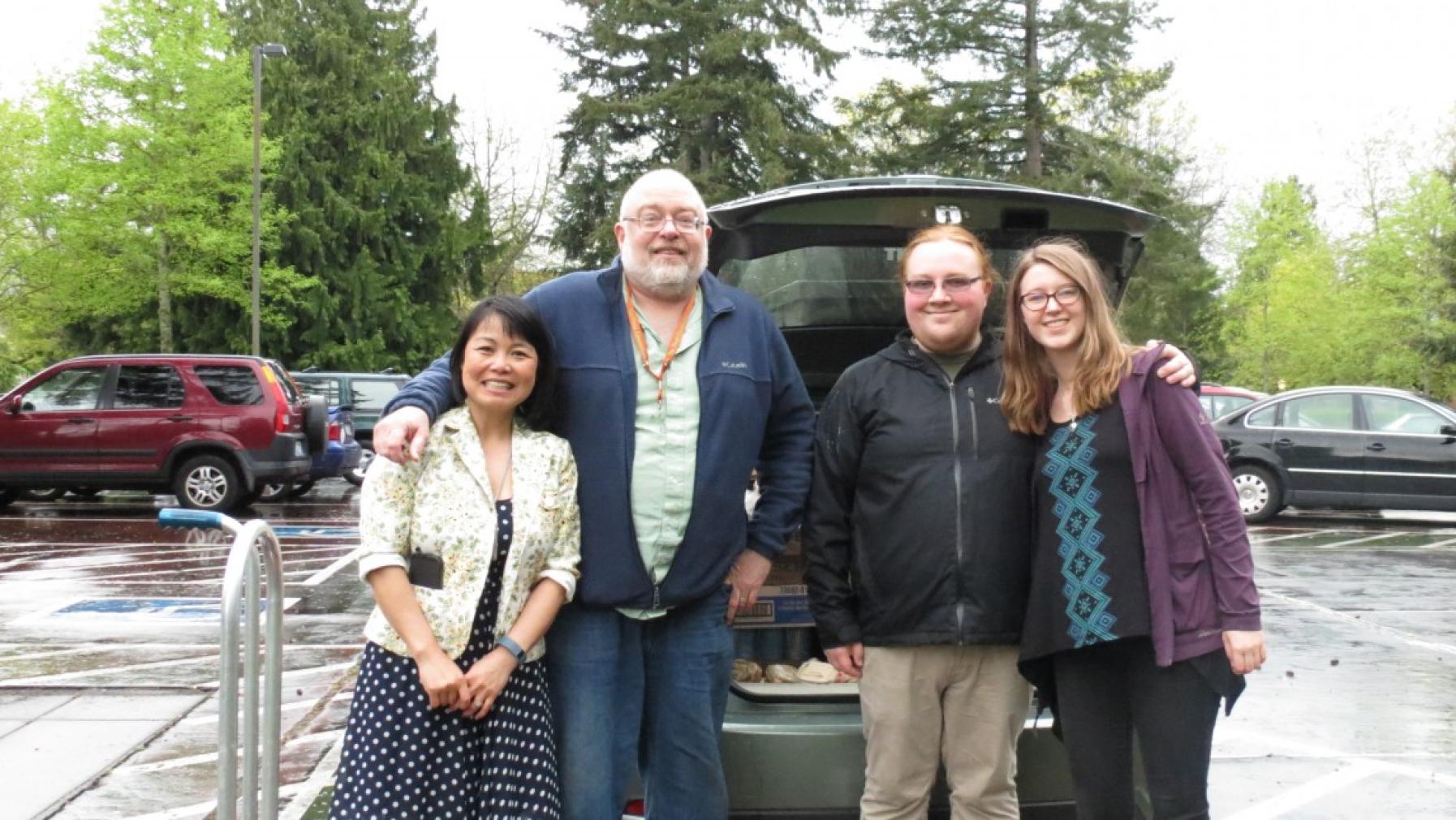 Four people standing in front of a car.