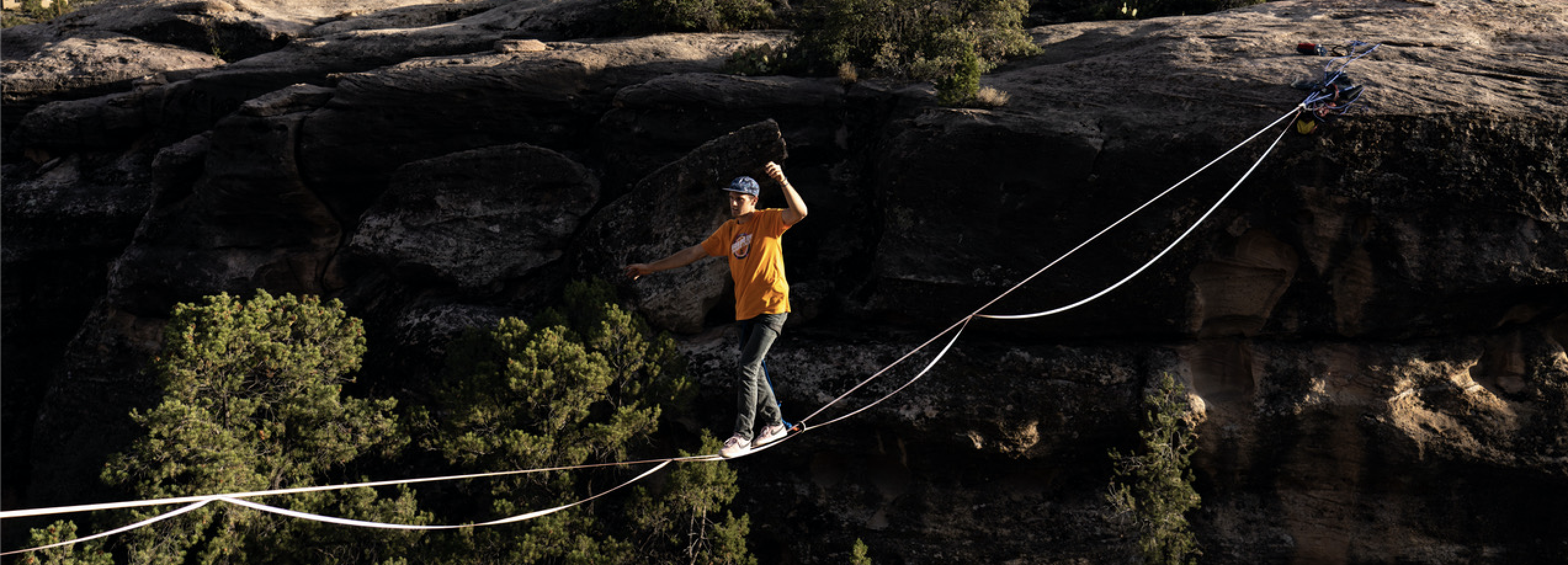 A person walking across a tightrope between two cliffs