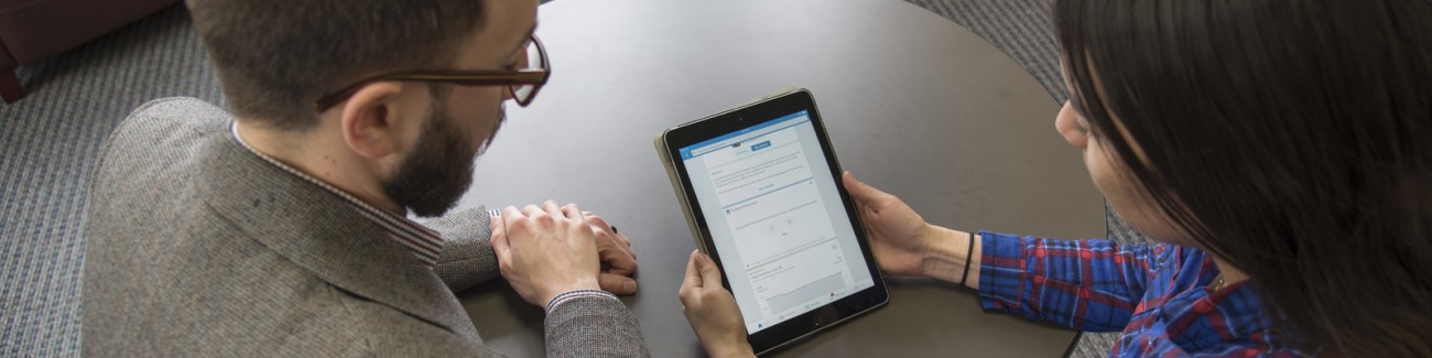 Two people at a table looking at a tablet screen