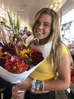 Student smiling at the camera while holding a flowers