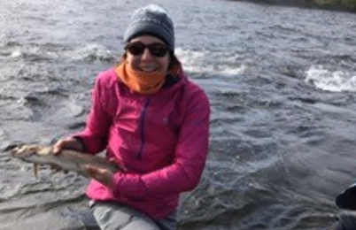 Georgia Sans Daniels holding a fish on the water’s edge