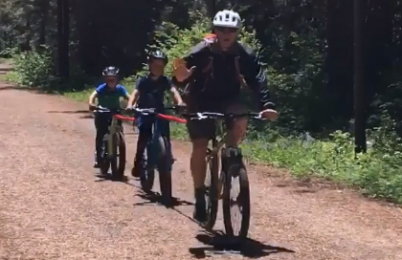 An adult and two children riding bicycles on a trail
