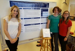 Three people smiling beside an informational display