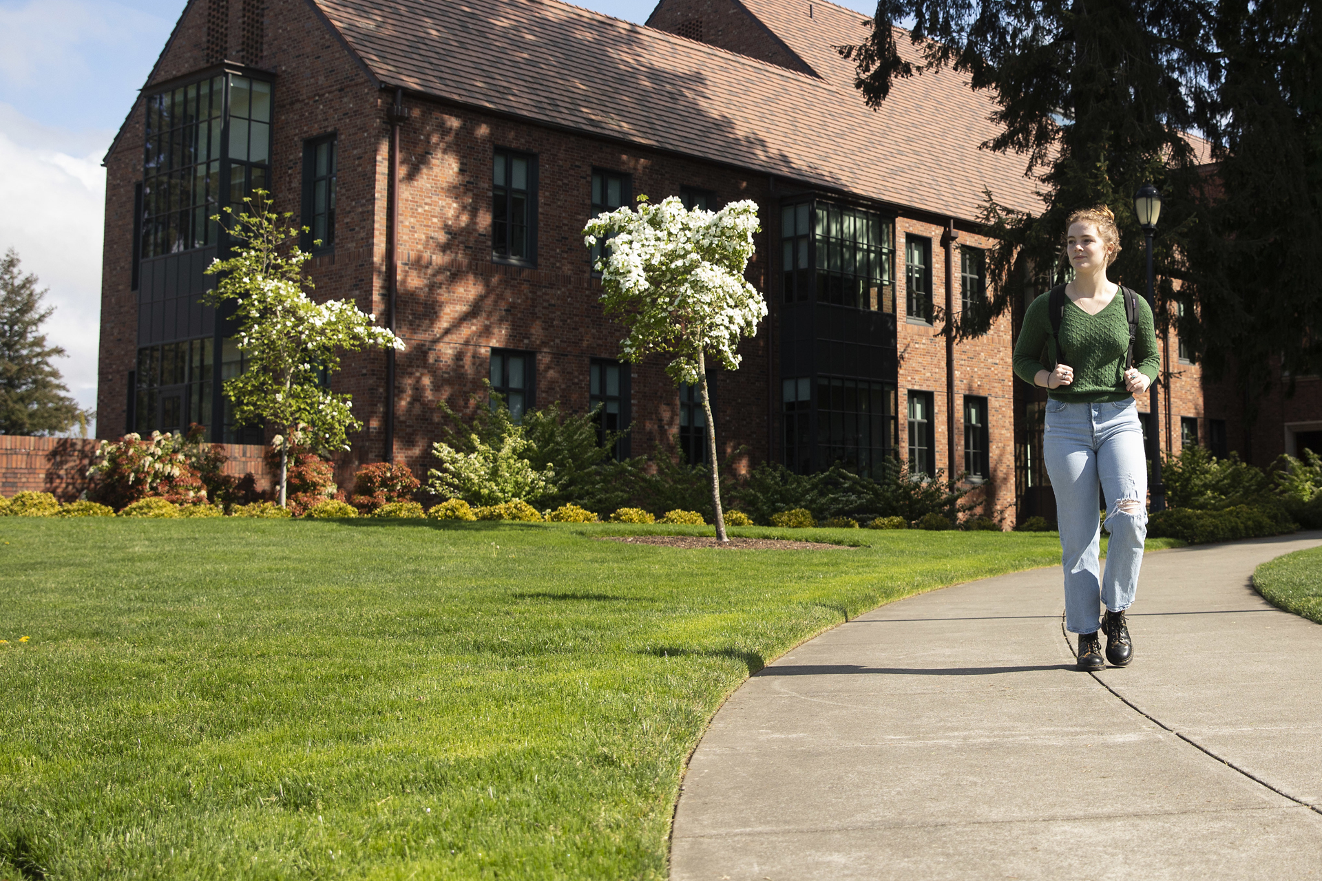 A student walks along Commencement Walk with Weyerhaeuser Hall in the background