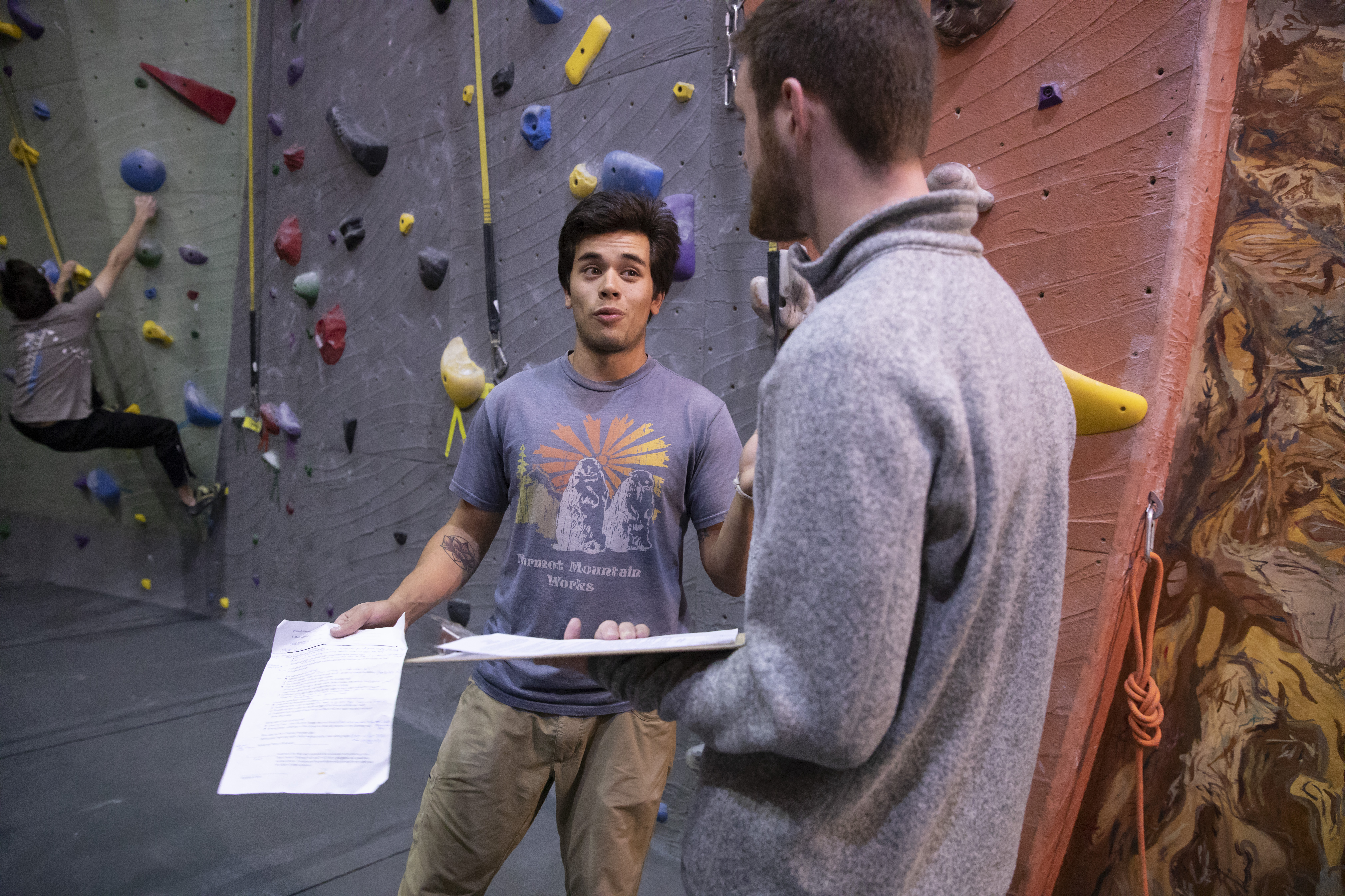 A climbing wall staff goes through the climbing wall orientation process with a student.
