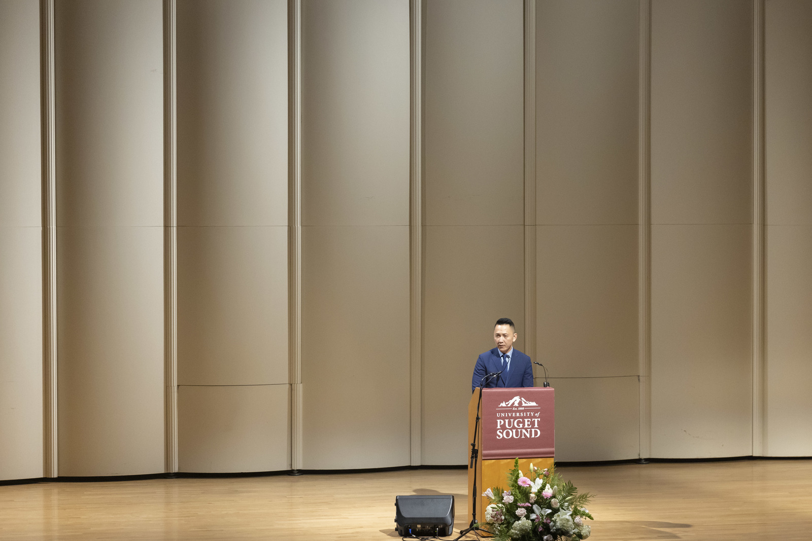 Viet Thanh Nguyen stands at a podium onstage at Schneebeck Concert Hall