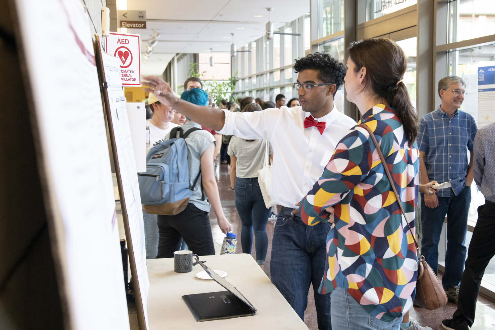 Male student shares research poster with female guest