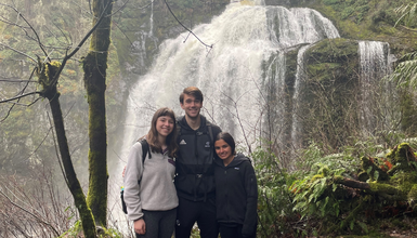 Three people standing in front of a waterfall