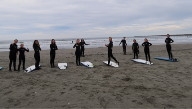 A group of people wearing wetsuits on the beach with surfboards