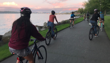 People riding bikes on a path beside the water