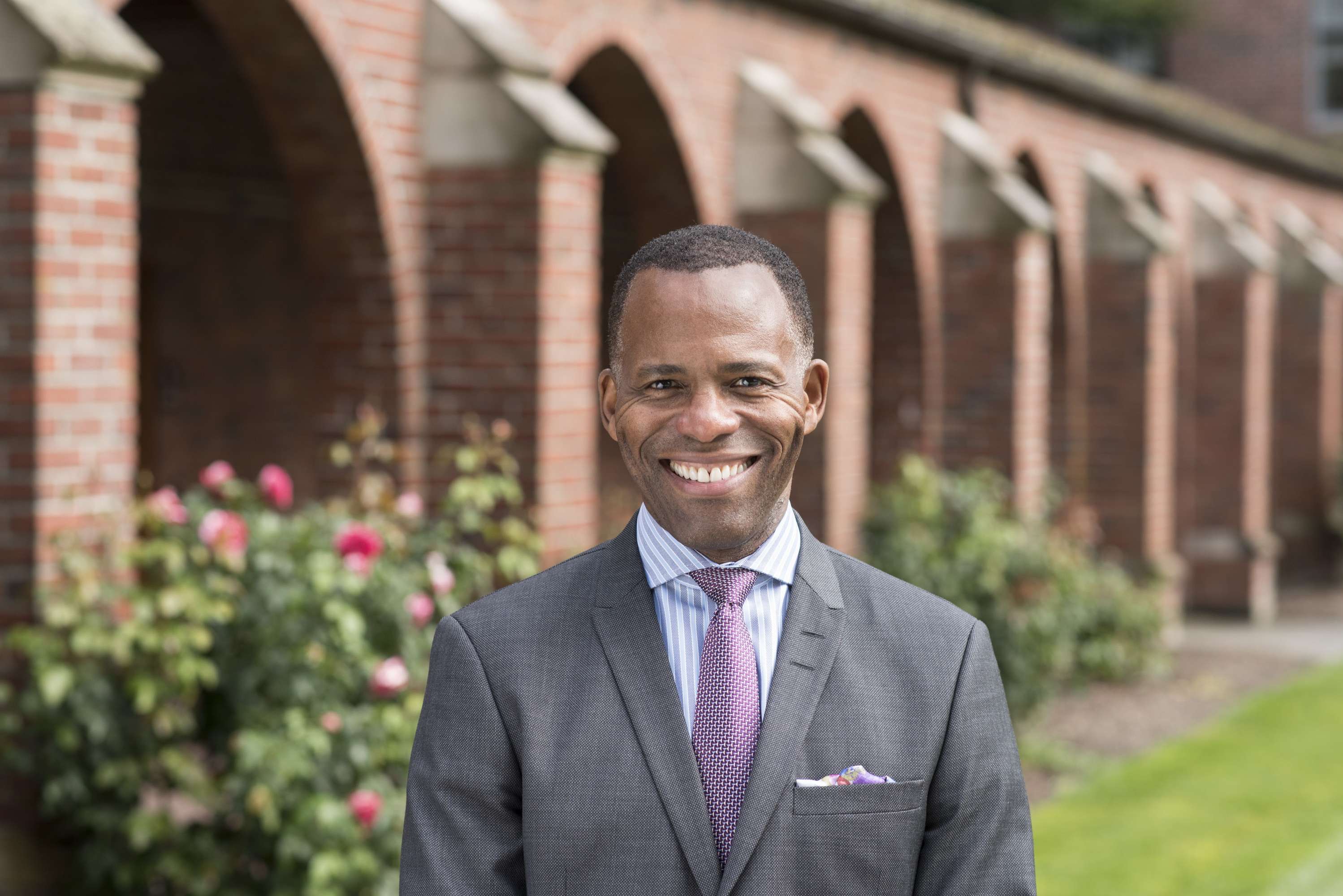 President Isiaah Crawford smiles at the camera as he stands in front of the campus arches. 