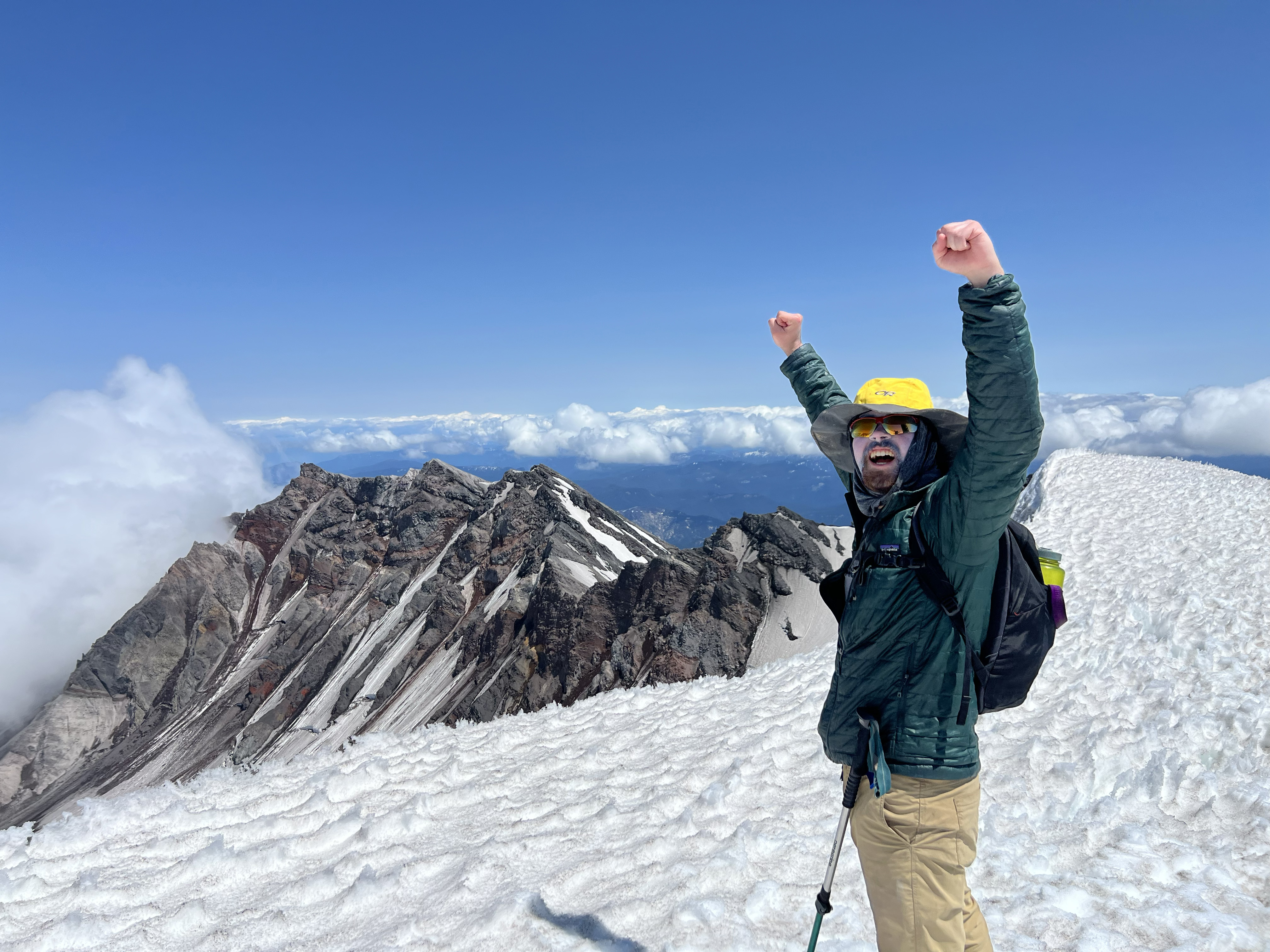 A PacTrail student raises their hands in victory at the summit of Mount St. Helens.