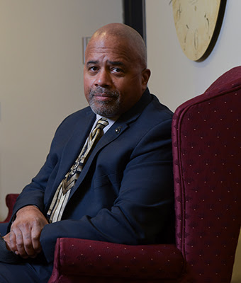 Dr. Fred Johnson III, sits in a maroon chair facing the camera. 