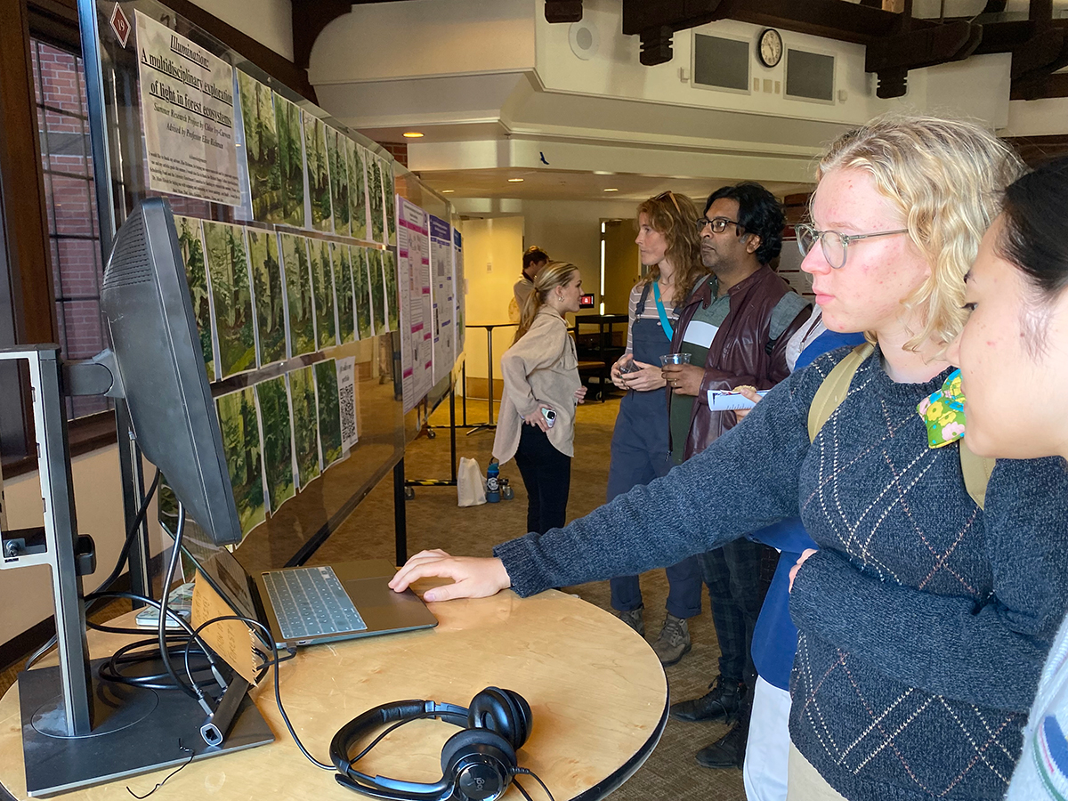 Students and faculty examine Chloe Ivy-Curwen’s project at the Summer Research Symposium, 2024