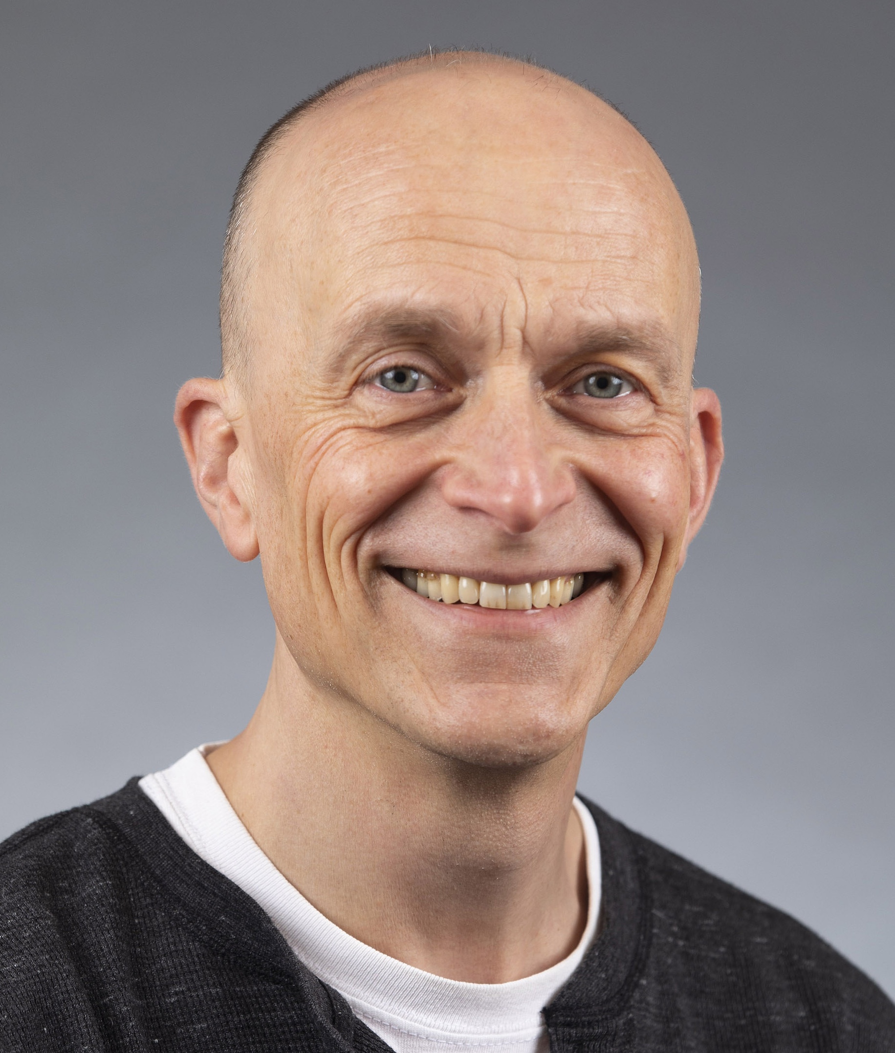 Man with short hair in a black shirt and white undershirt. 