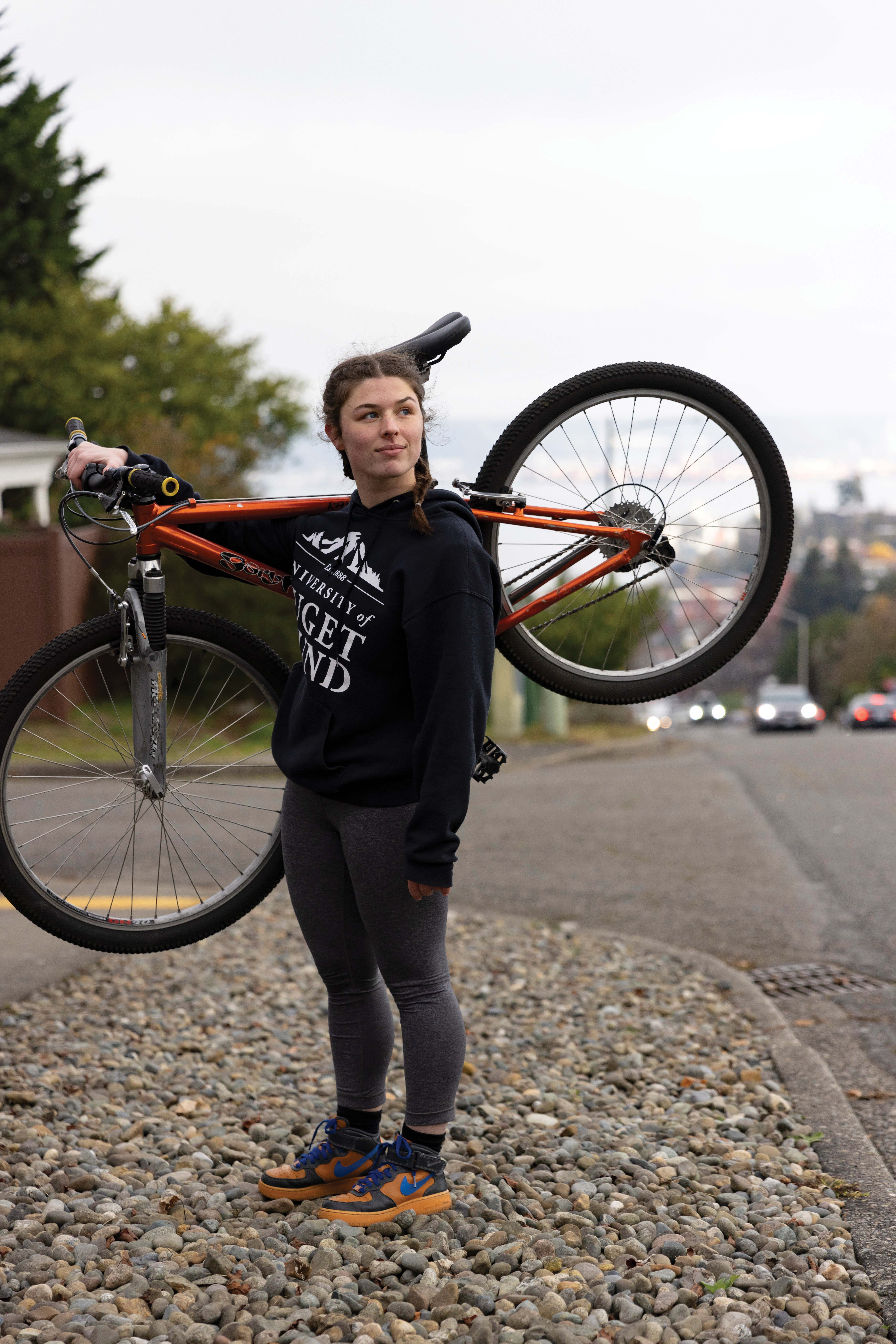 Emma Smith ’24 with her bike over her shoulder at the top of the 30th St. hill in Tacoma.