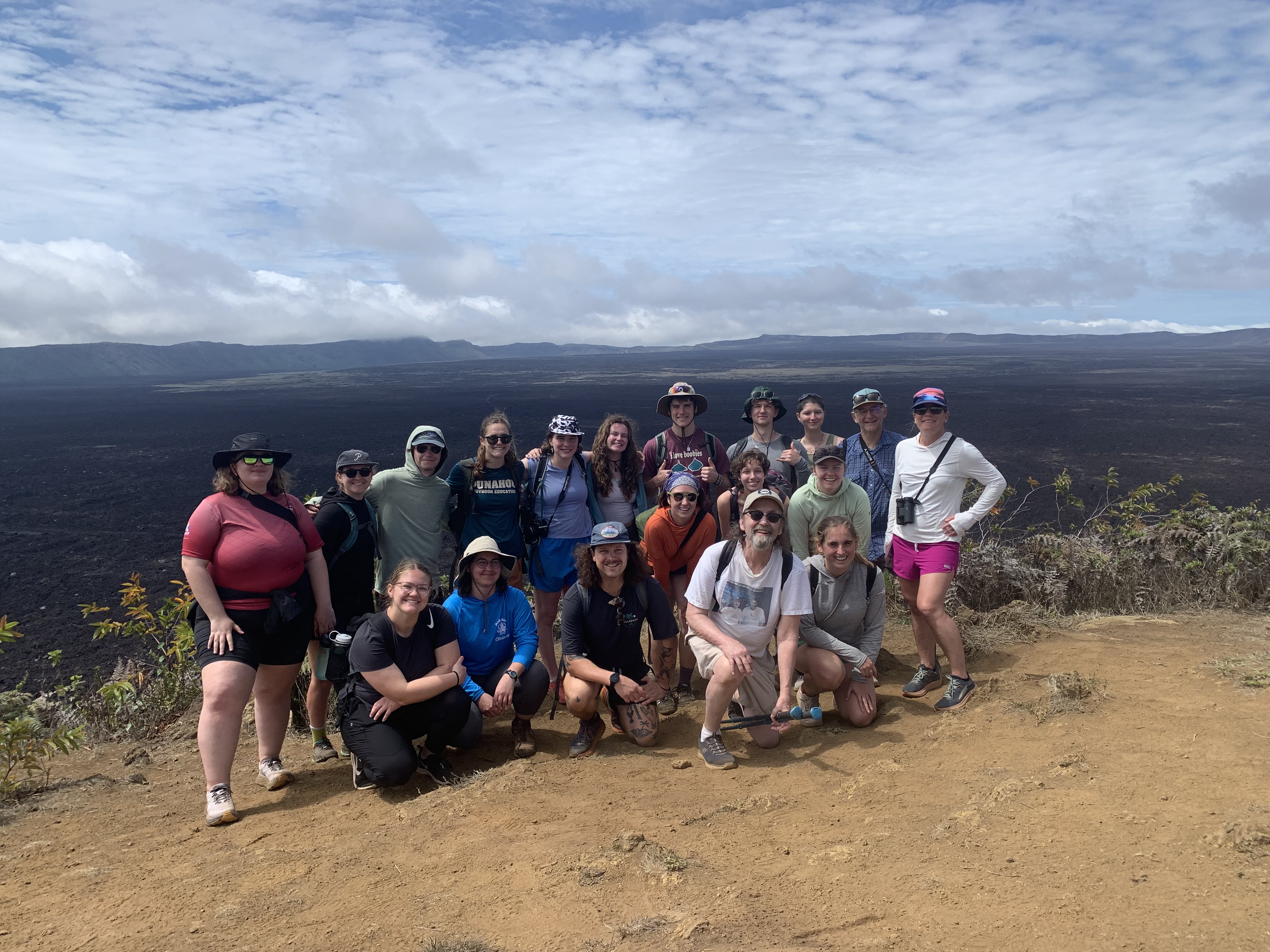 Student, alumni and faculty pose at a volcano site 