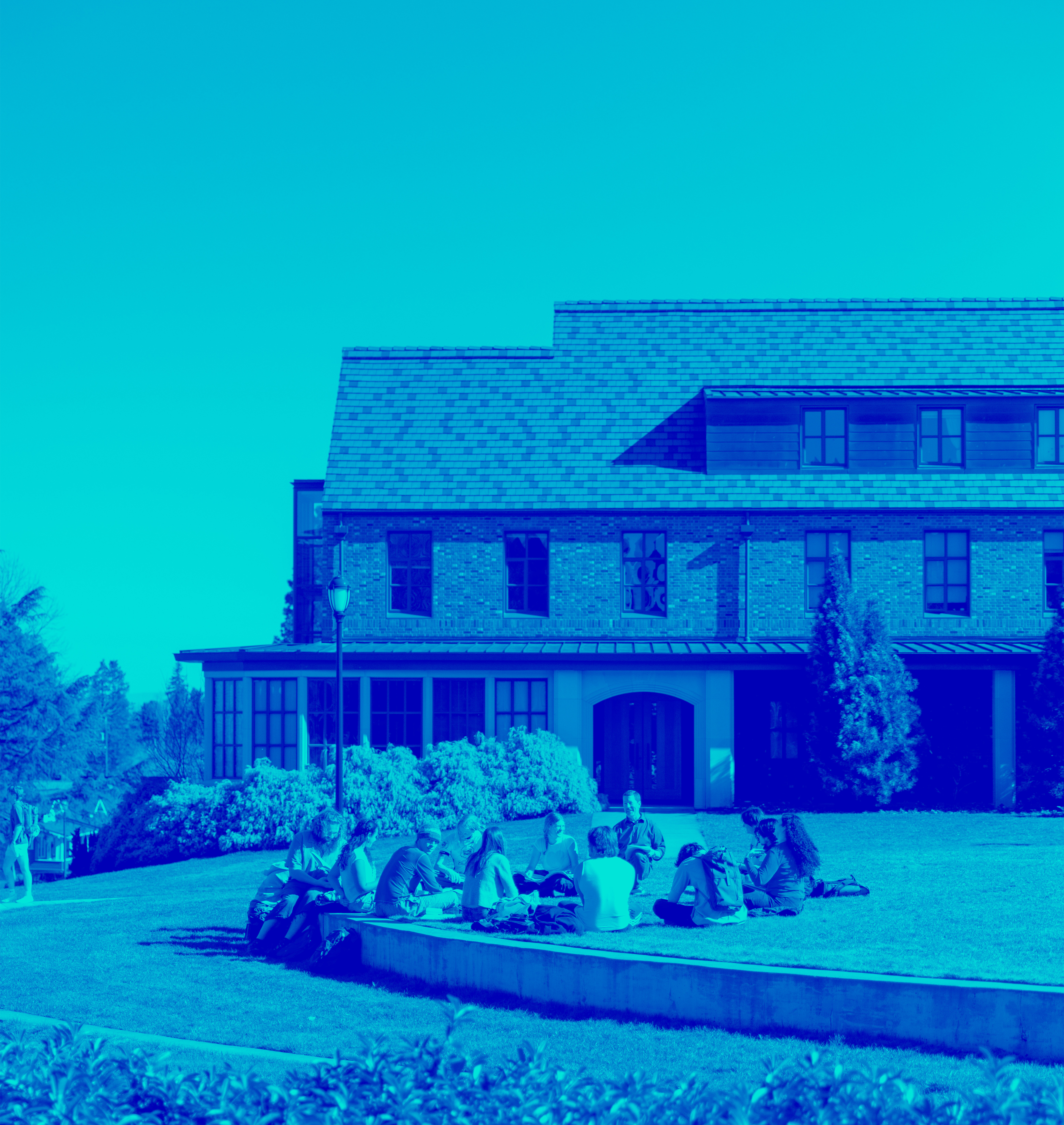 Blue tonal image of students sitting outside for a class.