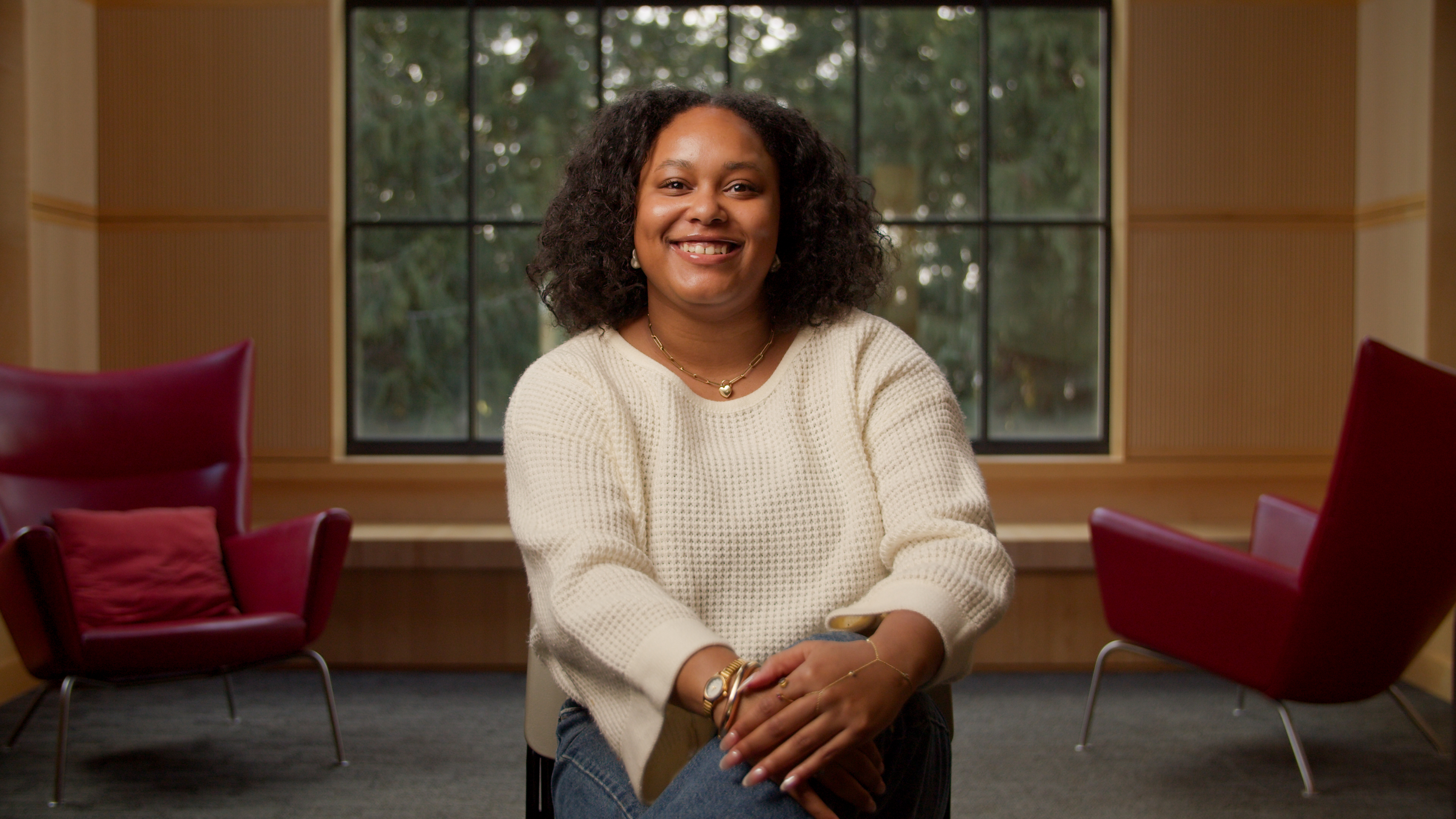 Kevoni Neely sits in front of a big window in a white sweater. 