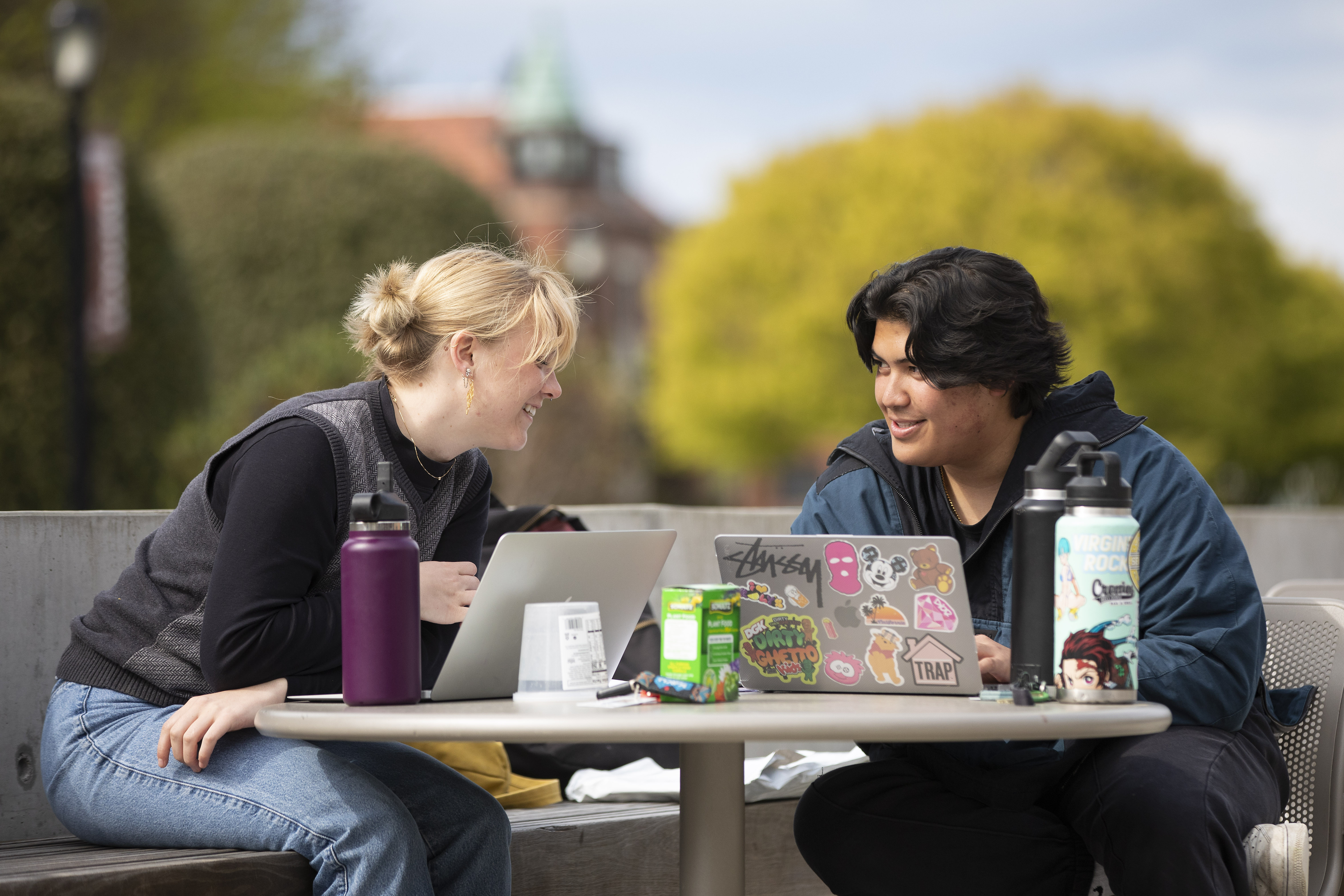 Two students chat over laptops on a sunny day on Wheelock Plaza.