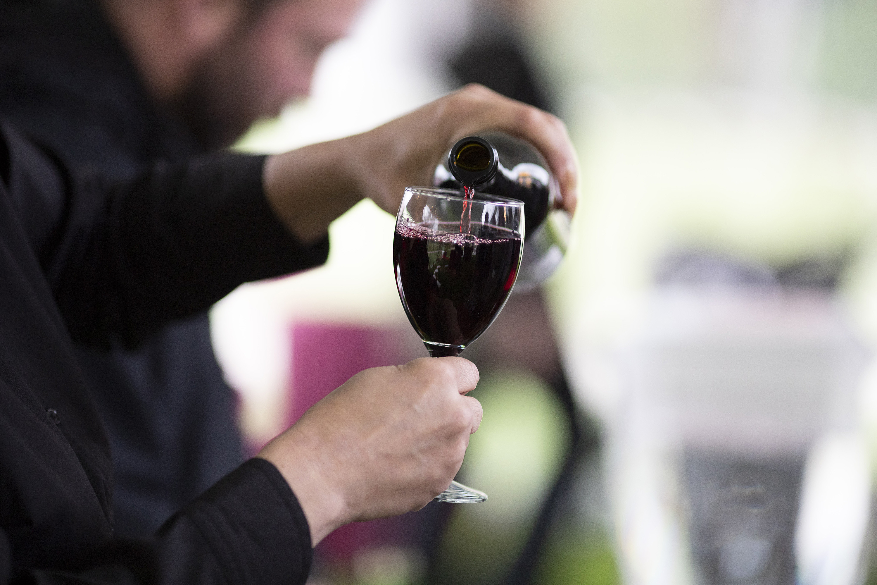 A glass of red wine being poured.