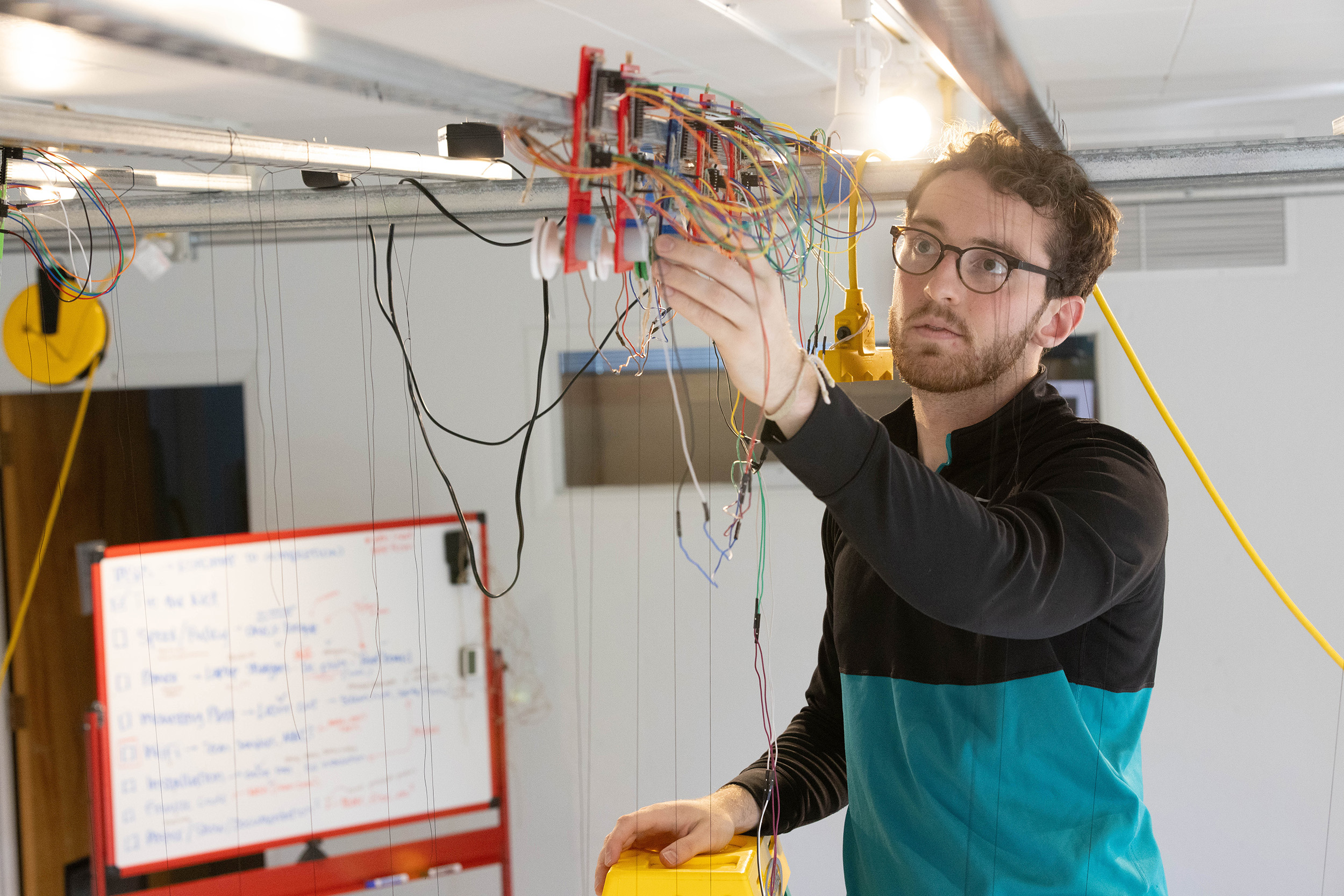 Josh Cunningham ’25 examines one of the stepper motors powering his kinetic sculpture.