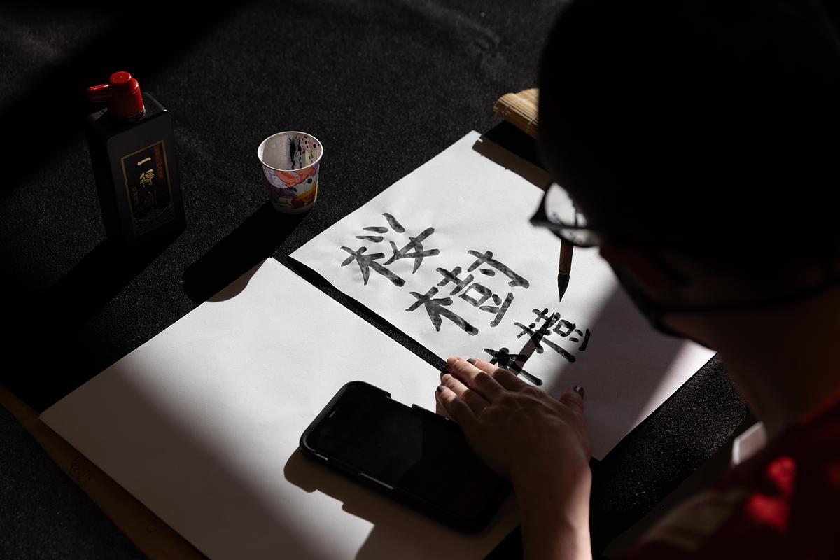 A shadowed person writing Japanese Calligraphy