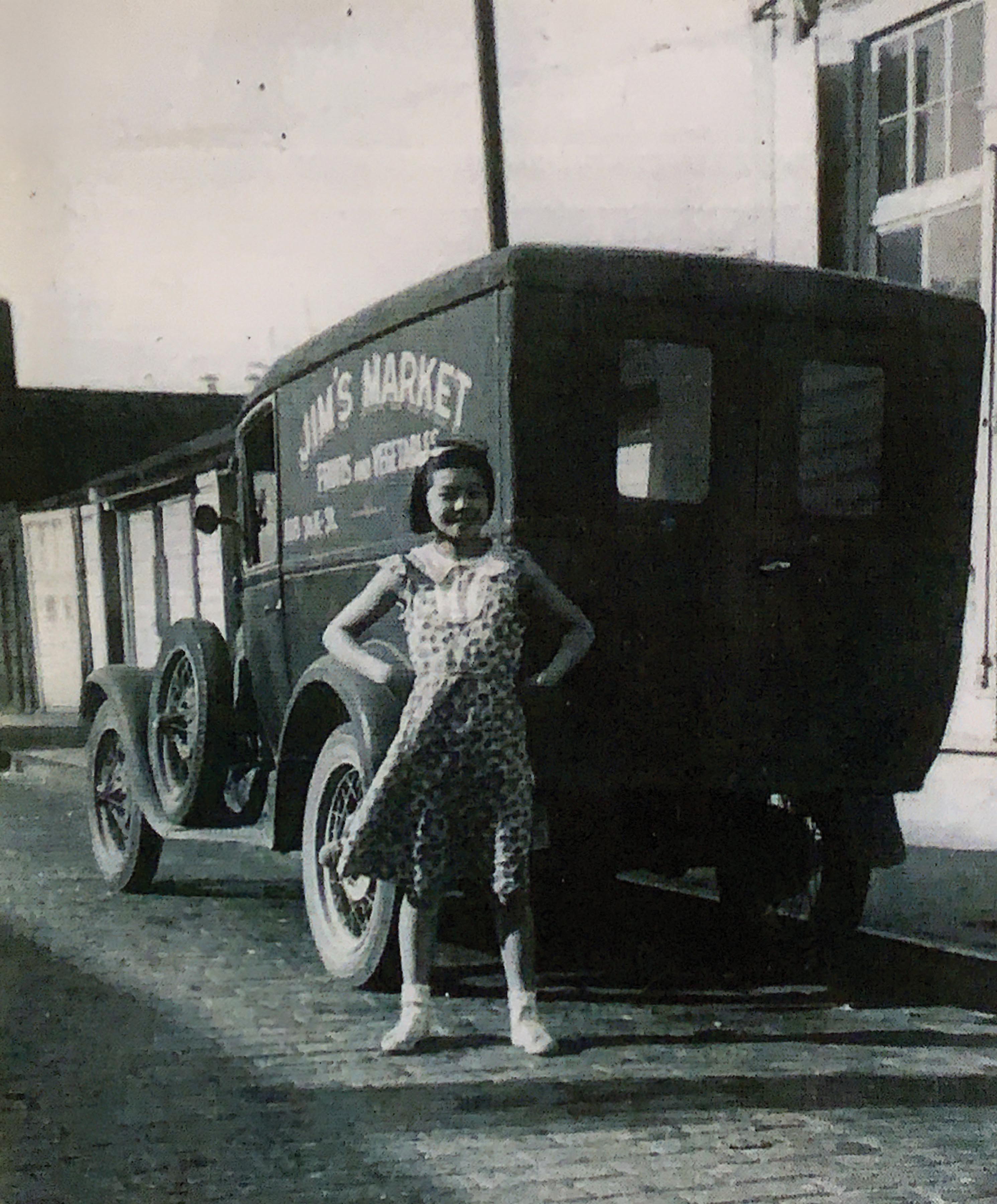 A young Michiko Jinguji poses in front of her father’s grocery truck in Tacoma in the 1930s.