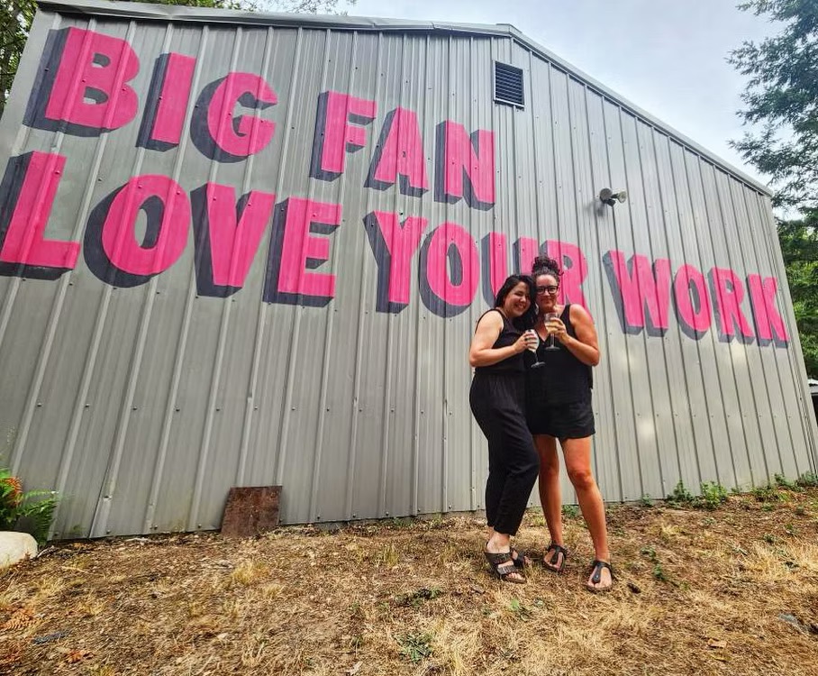 Producers Cessa Betancourt and Prof. Jess K Smith in front of the Big Fan, Love Your Work mural.