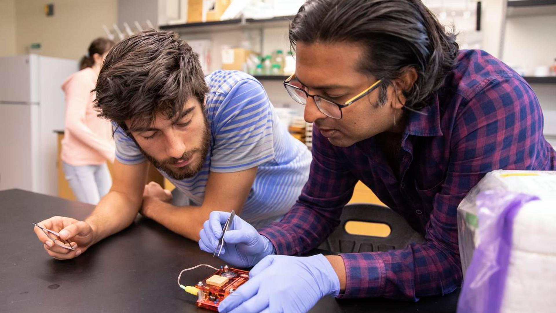 A professor assists a student with lab research.