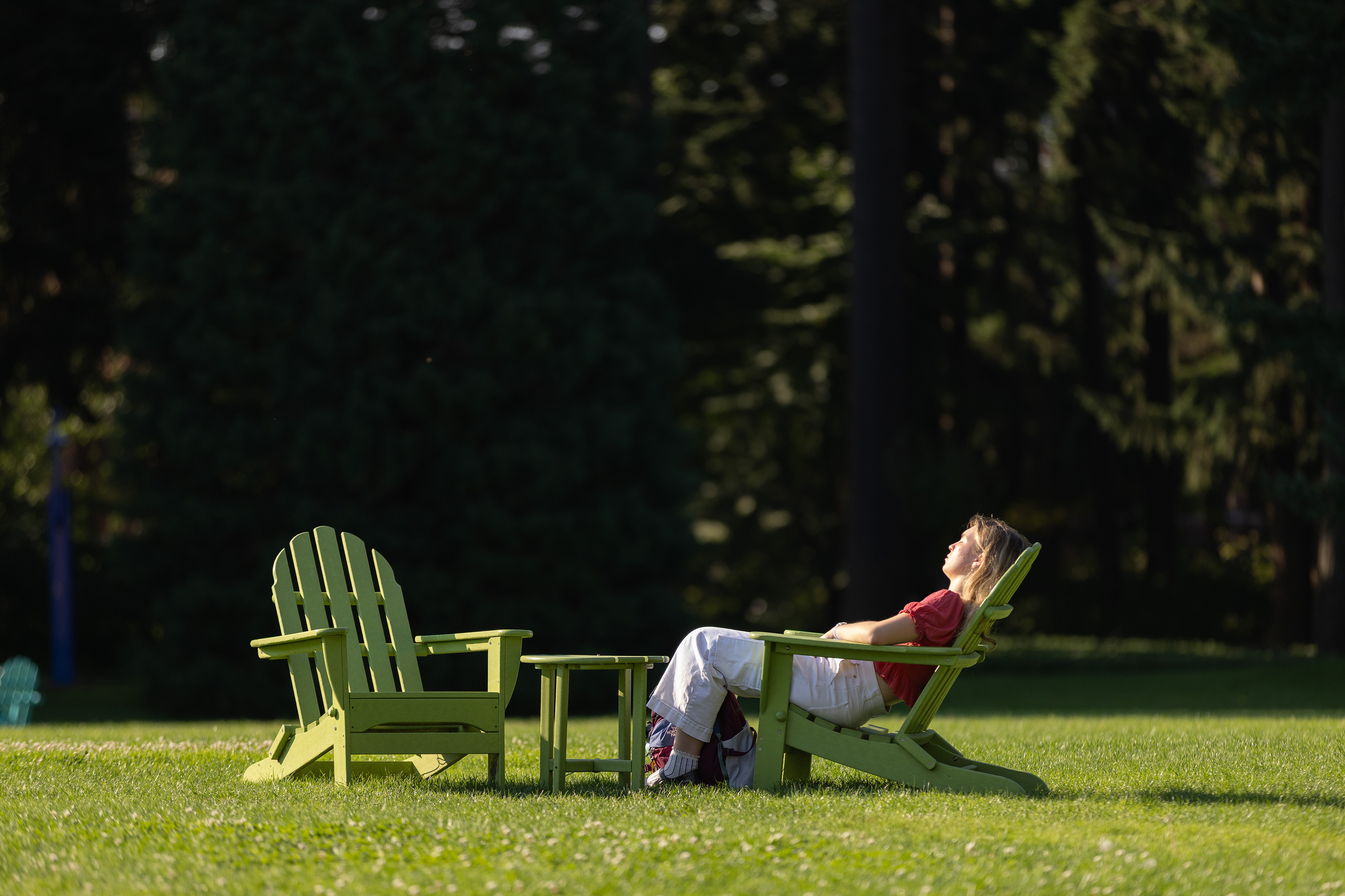 Student enjoys the sun while sitting in an Adirondack chair.