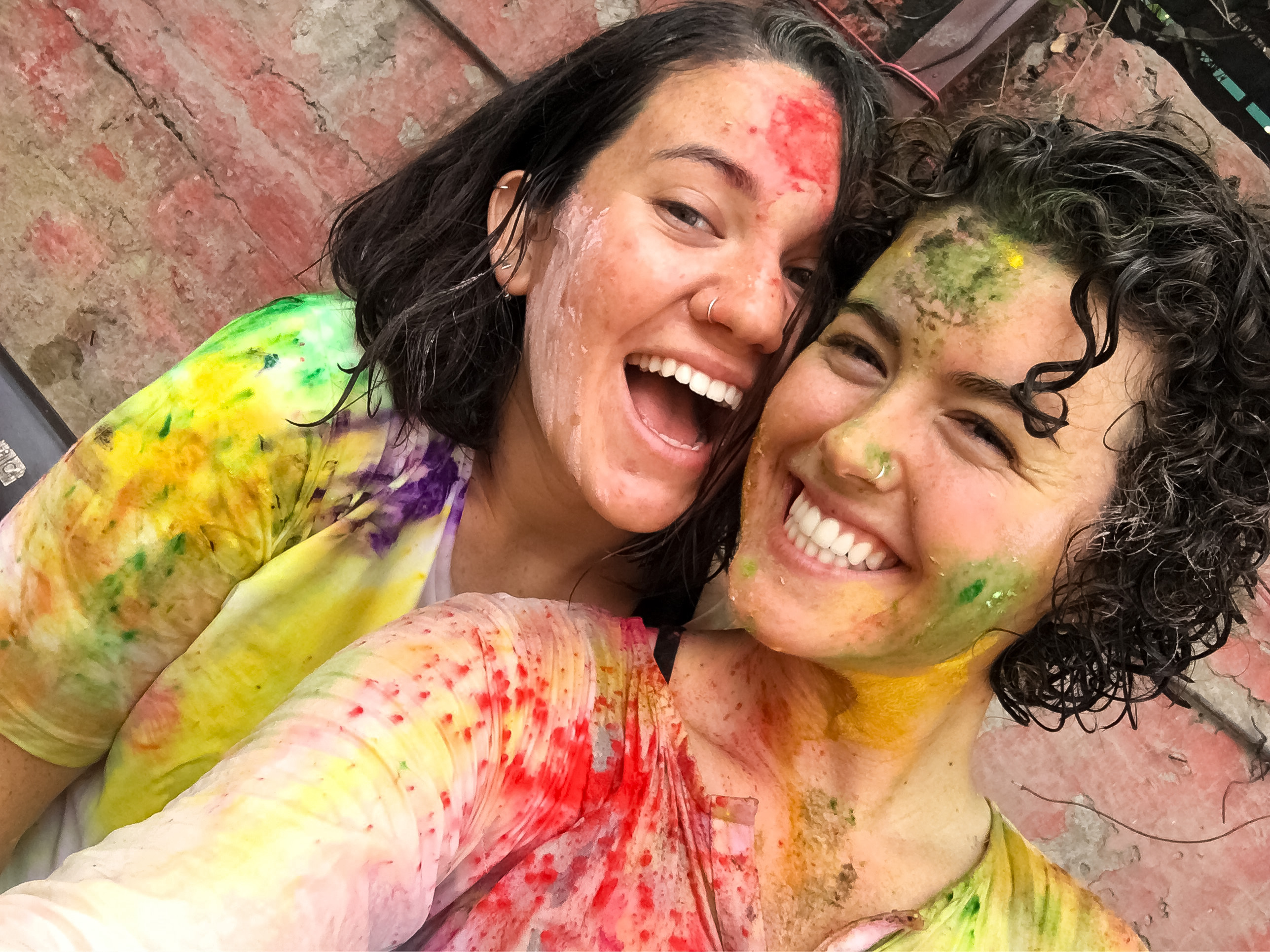 Two smiling students covered in colorful paint