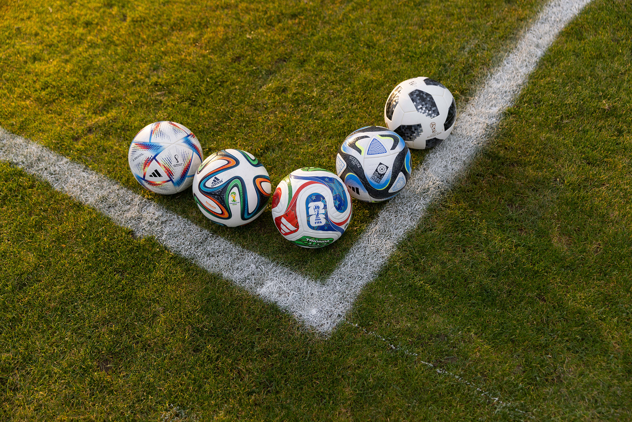 World Cup soccer balls arranged near the a corner on the field.