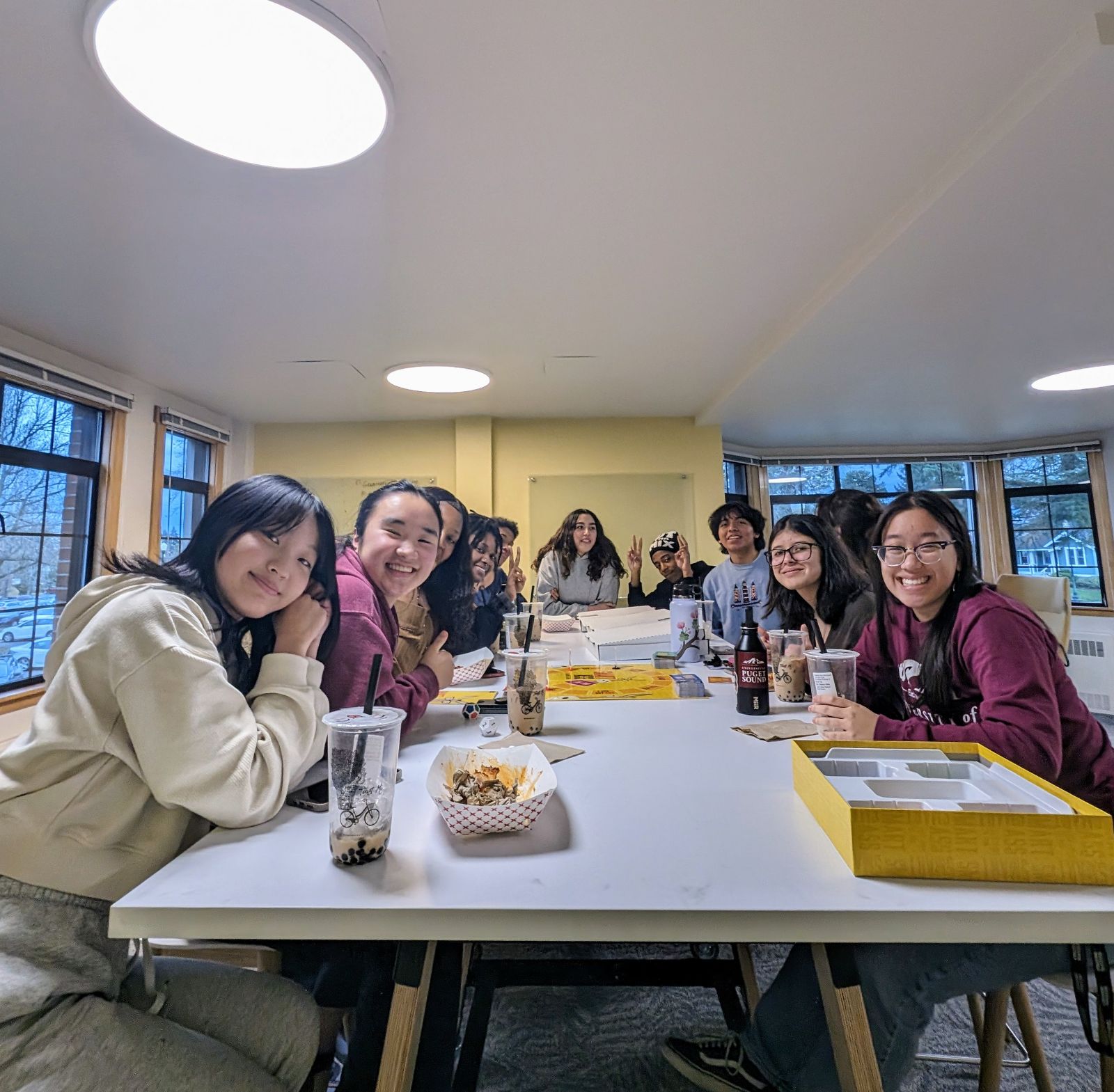 students sitting around table, smiling at camera