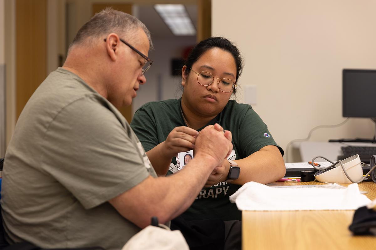 A student assists a patient in the OT Clinic.
