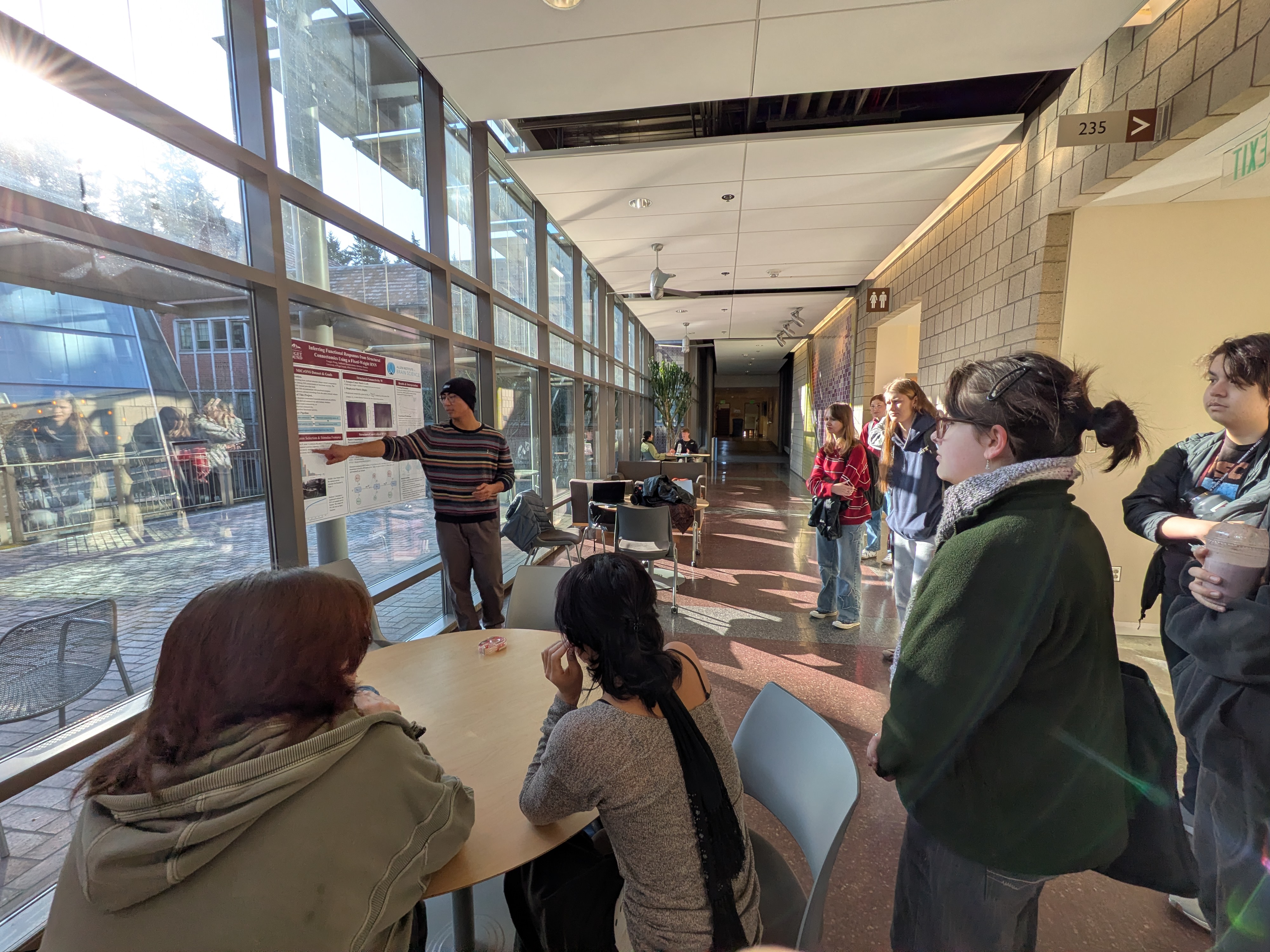 A student points at a science poster as a group of students look on. 
