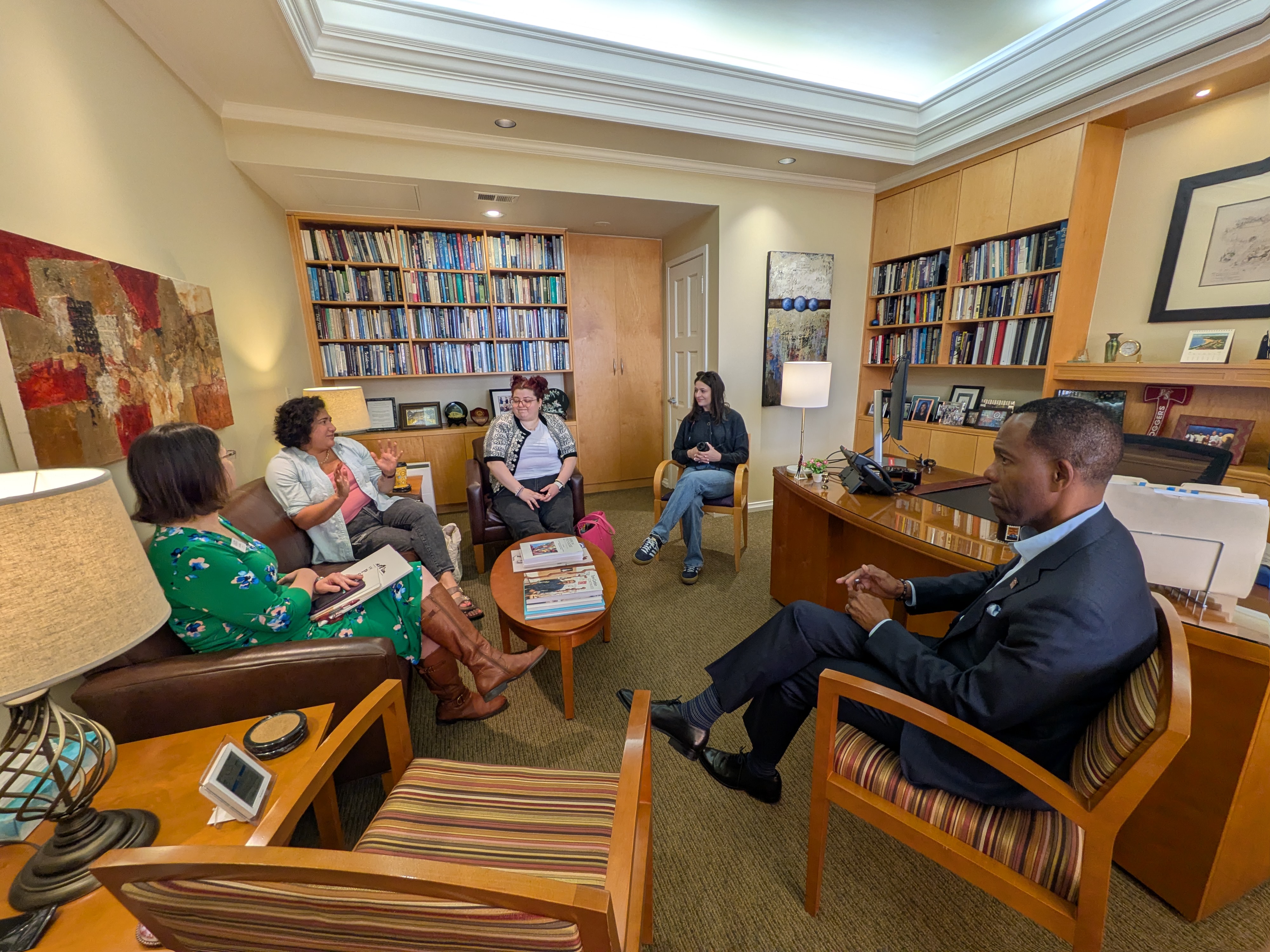 Five people sit in a circle in an office. 