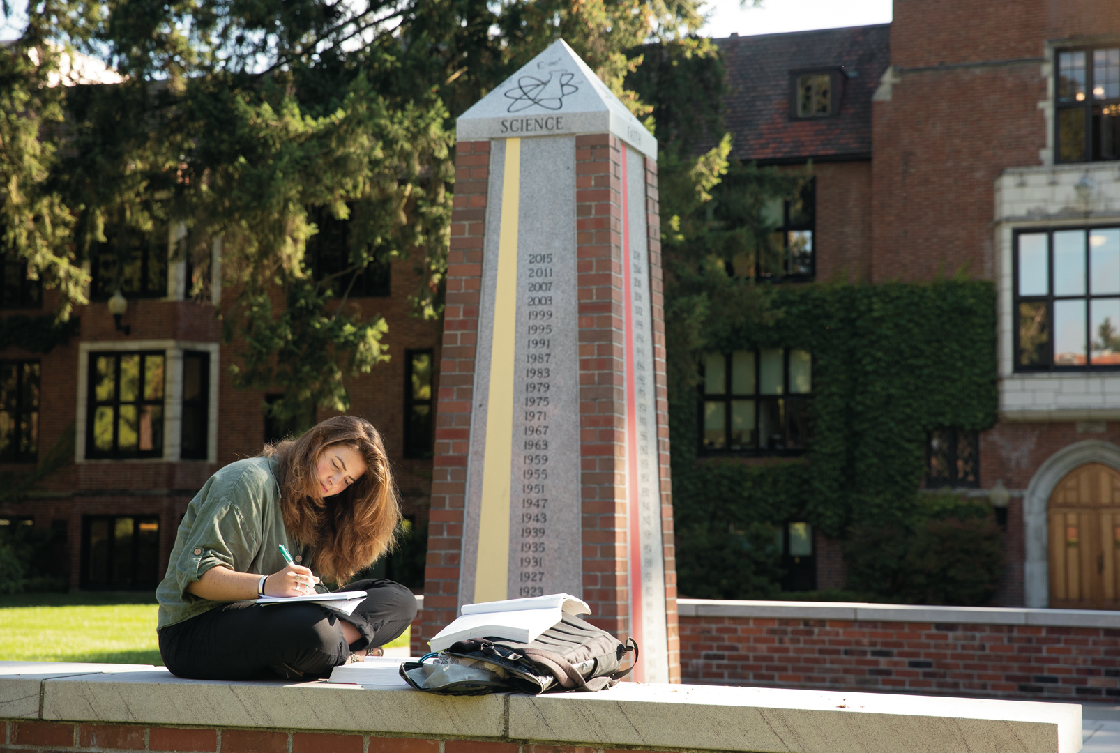 Student seated in front of the Karlen Quad granite obelisk