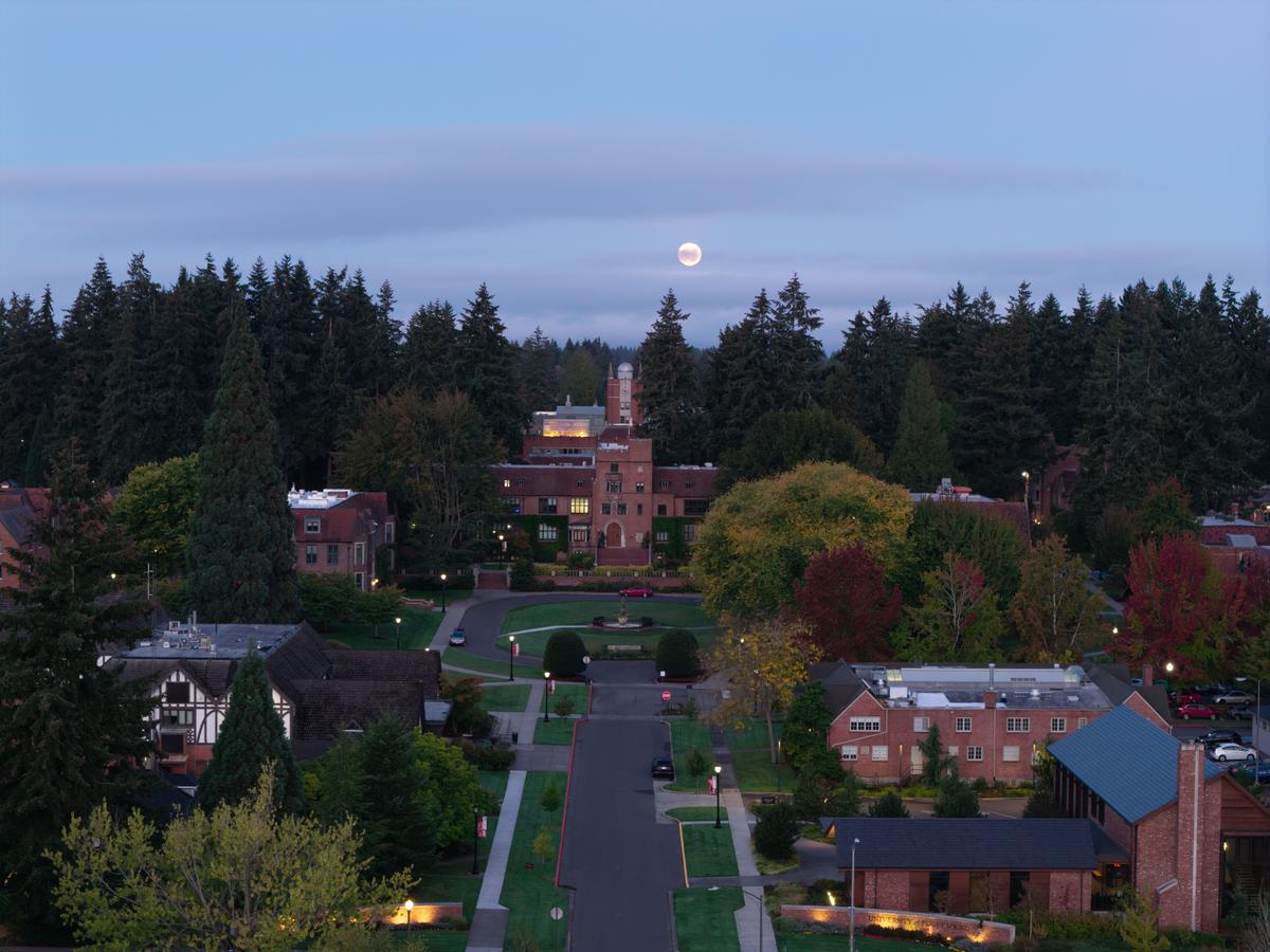 Drone photo of UPS campus at night with a full moon overhead