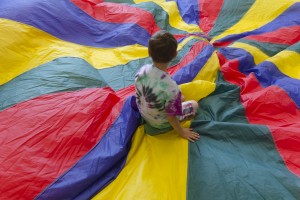 Child seated on colorful parachute silk material