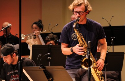 A person playing a saxophone with a band.