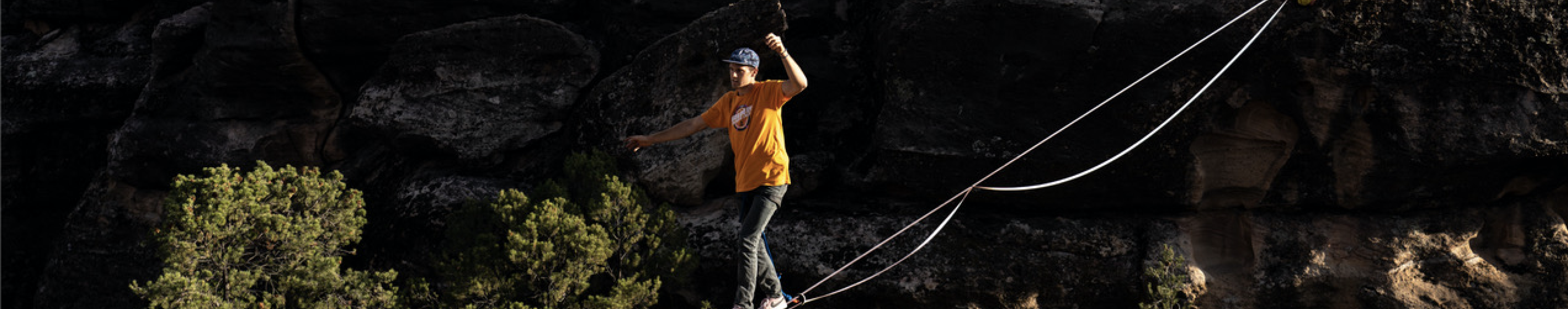 A person walking across a tightrope between two cliffs